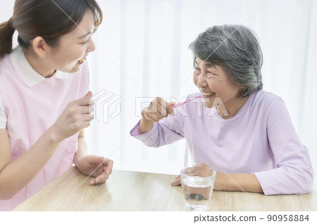 A young dental hygienist who teaches seniors to brush their teeth 90958884