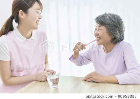 A young dental hygienist who teaches seniors to brush their teeth A young dental hygienist who teaches seniors to brush their teeth 90958885