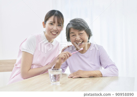 A young dental hygienist who teaches seniors to brush their teeth A young dental hygienist who teaches seniors to brush their teeth 90958890