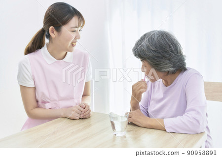 A young dental hygienist who teaches seniors to brush their teeth A young dental hygienist who teaches seniors to brush their teeth 90958891