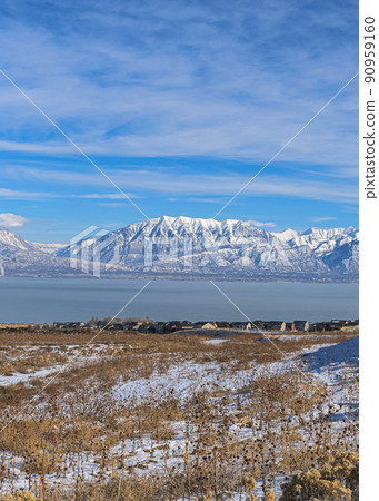 Vertical A panoramic view of the snowy wasatch mountains with the clear blue sky in the background Vertical A panoramic view of the snowy wasatch mountains with the clear blue sky in the background 90959160