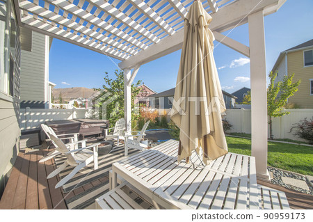 Empty patio exterior of a house and a table that has a closed umbrella. 90959173