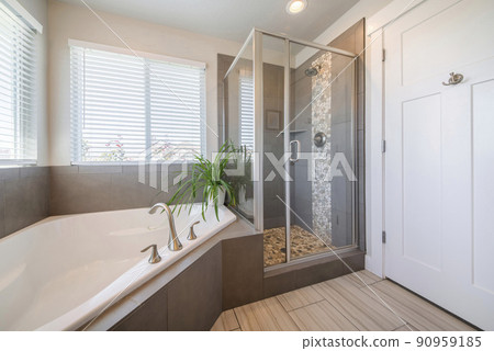 Inside of a bathroom with closed white door with hooks and tile floor Inside of a bathroom with closed white door with hooks and tile floor 90959185