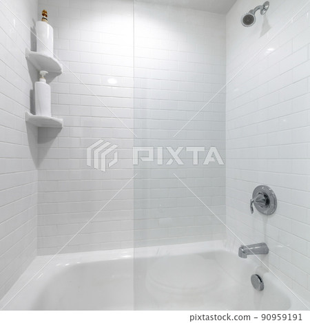 Square frame Alcove bathtub with glass wall divider and a wall with white tiles 90959191