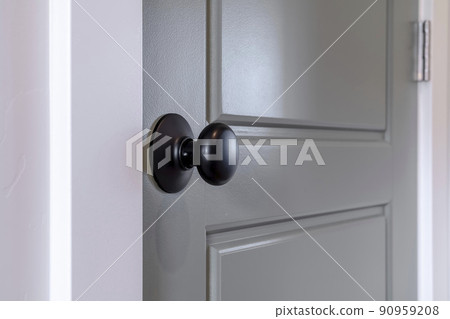 Gray wooden hinged door with black door knob and panels inside of home Gray wooden hinged door with black door knob and panels inside of home 90959208