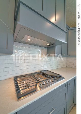 Residential kitchen interior with cooktop stove on countertop under exhaust hood 90959220