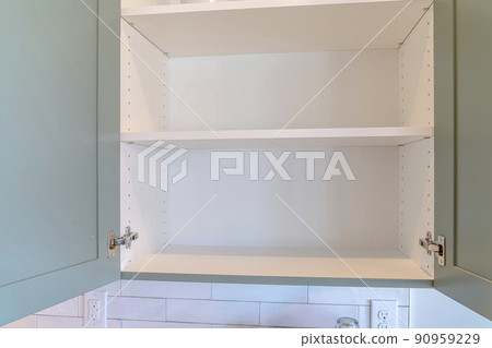 Hanging wall cabinet with open doors and empty shelves inside kitchen of home 90959229