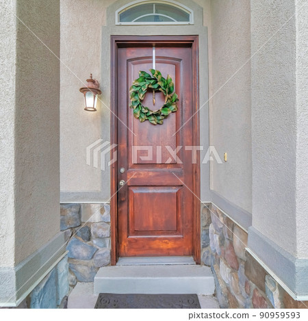 Square Wooden front door of a house with transom window and leafy wreath at the front Square Wooden front door of a house with transom window and leafy wreath at the front 90959593