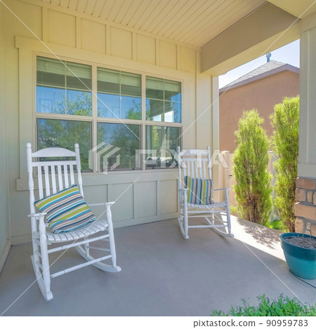 Square Two white rocking chairs with striped pillows on a porch of a house Square Two white rocking chairs with striped pillows on a porch of a house 90959783