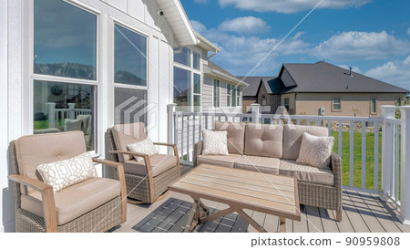 Panorama White puffy clouds Outdoor patio on a wooden deck with cushioned woven sofa and arm Panorama White puffy clouds Outdoor patio on a wooden deck with cushioned woven sofa and arm 90959808