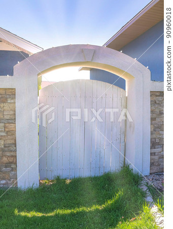 Vertical Sun flare Wooden backyard gate with concrete arched entrance and stone veneer fence 90960018