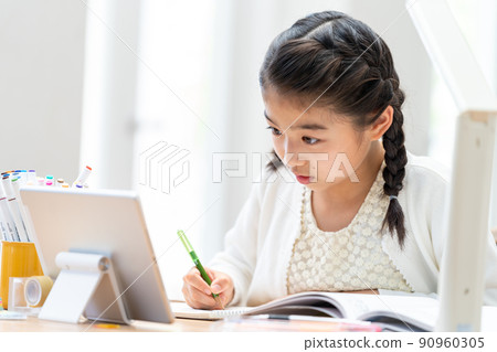 Elementary school girl studying while looking at a tablet 90960305