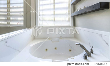 Pano Bathtub with marble surround inside a bathroom against the window Pano Bathtub with marble surround inside a bathroom against the window 90960614