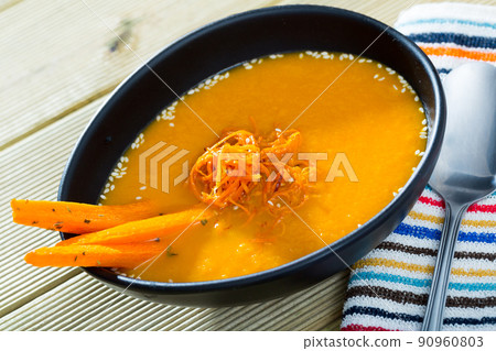 Tasty boiled vegetarian carrot cream soup served at plate on table 90960803