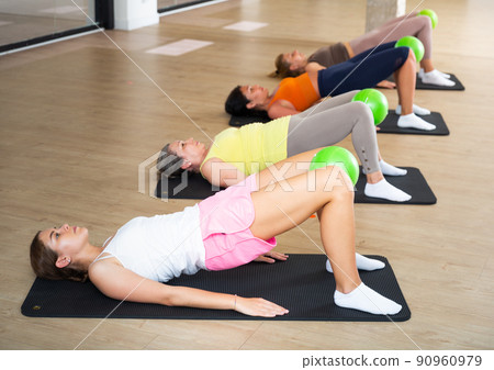 Women doing hip bridge with pilates ball 90960979