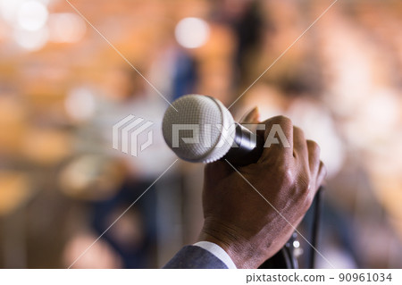 Male hand holding microphone at conference hall Male hand holding microphone at conference hall 90961034