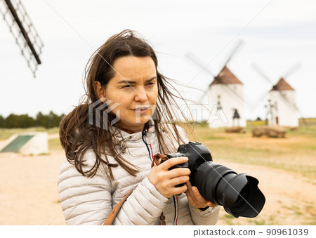 Woman tourist takes pictures of the windmills of Mota del cuervo. Spain Woman tourist takes pictures of the windmills of Mota del cuervo. Spain 90961039