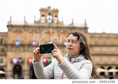 Woman is taking photos on her camera while journey through the Plaza Mayor. Spain Woman is taking photos on her camera while journey through the Plaza Mayor. Spain 90961096