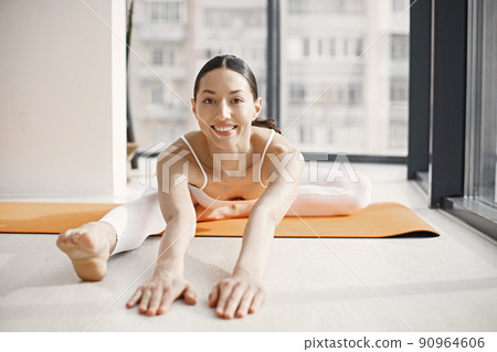 Slim and beautiful woman wearing beige leggins and top and stretching on yoga mat. Young girl with fit body posing at bright studio with big windows. Sport, fitness, diet, nutrition and health care Slim and beautiful woman wearing beige leggins and top and stretching on yoga mat. Young girl with fit body posing at bright studio with big windows. Sport, fitness, diet, nutrition and health care 90964606