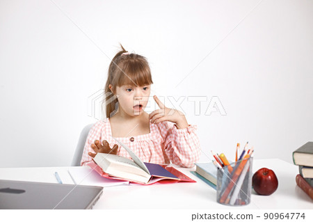 Sunny girl with Down syndrome sitting at desk. Girl studying alone at home. Education for disabled children concept. Sunny girl with Down syndrome sitting at desk. Girl studying alone at home. Education for disabled children concept. 90964774