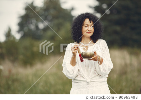 Woman holding chanting bowl in nature setting Woman holding chanting bowl in nature setting 90965498