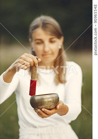 Woman holding chanting bowl in nature setting Woman holding chanting bowl in nature setting 90965548