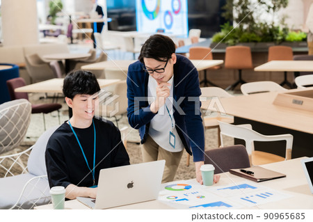 A boss who teaches with a newcomer who is taught work in office casual 90965685