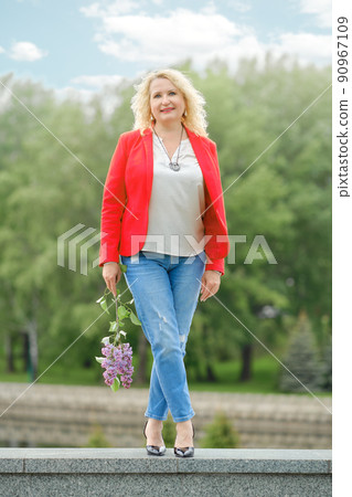 Beautiful middle age woman with lilac branch in hand Beautiful middle age woman with lilac branch in hand 90967109
