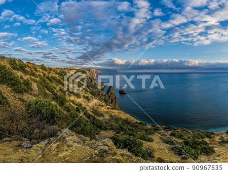 Summer seascape with Fiolent rocks formation on the coast of Sevastopol. view on cape in the sea, clear azure water, calm hot day. Copy space. The concept of calmness, silence and unity with nature. Summer seascape with Fiolent rocks formation on the coast of Sevastopol. view on cape in the sea, clear azure water, calm hot day. Copy space. The concept of calmness, silence and unity with nature. 90967835