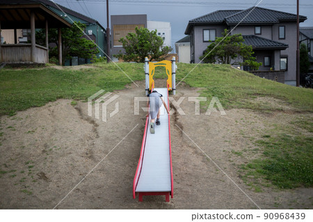 A girl in elementary school playing on a slide in a park in a residential area 90968439