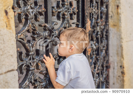 Boy peeking through a hole in the fence Boy peeking through a hole in the fence 90970910