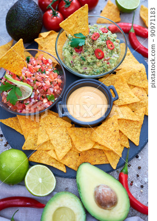 freshly made salsa and guacamole dip sauce with nacho chips on stone serving board freshly made salsa and guacamole dip sauce with nacho chips on stone serving board 90971183