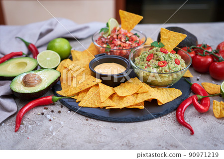 freshly made salsa and guacamole dip sauce with nacho chips on stone serving board 90971219