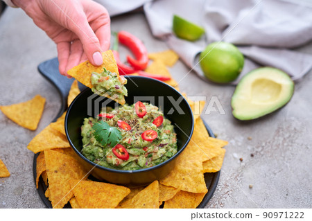 Guacamole dip with tortilla chips or nachos on black serving board 90971222