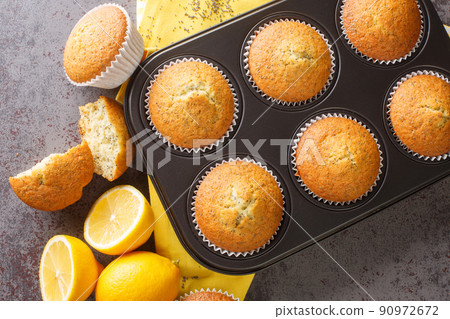 Homemade tender muffins with poppy seeds and lemon close-up in a metal muffin pan. horizontal top view 90972672