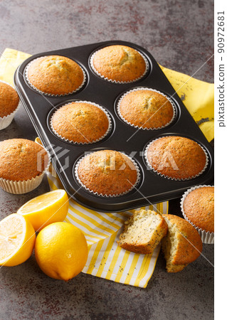 Freshly baked muffins with poppy seeds and lemon close-up in a baking dish. vertical 90972681