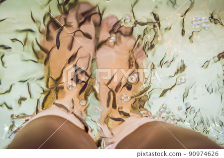 Young woman in a yellow dress at the fish spa Young woman in a yellow dress at the fish spa 90974626