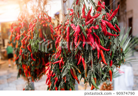 Bari, Puglia, Italy. August 2021. In the historic center, the old bari, a sales counter of the typical local chili pepper. Close up shot on bunch of chillies. 90974790