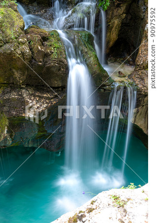 Beautiful image of blurred stream of waterfalls falling over mossy rocks 90975592