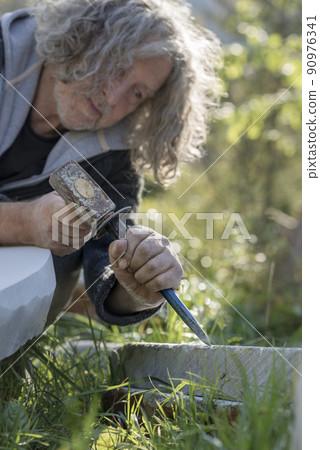 Senior sculptor sculpting in stone outdoors 90976341