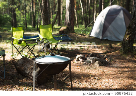 Cooking at a campsite on an open fire in a cauldron. Outdoor picnic, summer vacation, travel accessories Cooking at a campsite on an open fire in a cauldron. Outdoor picnic, summer vacation, travel accessories 90976432