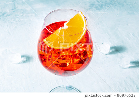 Aperol cocktail with a fresh orange slice and ice cubes, Italian summer drink 90976522