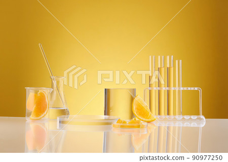 Front view of orange decorated with glassware and transparent podium in yellow background Front view of orange decorated with glassware and transparent podium in yellow background 90977250