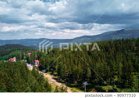 Aerial view of beautiful mountains, covered with forest and open cable car road. Karpacz resort in Poland with lift road. Family outdoor recreation in mountains Aerial view of beautiful mountains, covered with forest and open cable car road. Karpacz resort in Poland with lift road. Family outdoor recreation in mountains 90977310