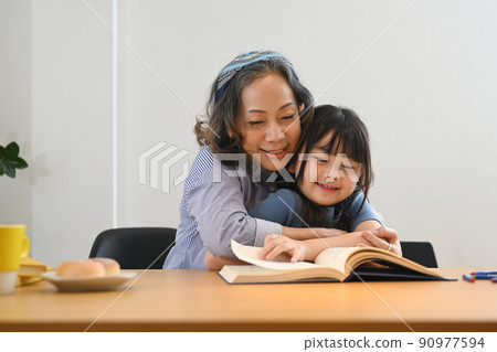 Caring grandma telling story, reading fairy tale to her little granddaughter. Multi generational, family and love concept Caring grandma telling story, reading fairy tale to her little granddaughter. Multi generational, family and love concept 90977594
