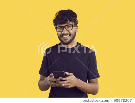 Smiling Indian man message online on cellphone 90978207