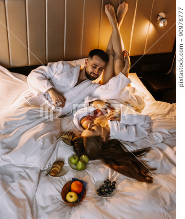 Happy young couple sitting in bed in morning and having breakfast 90978777