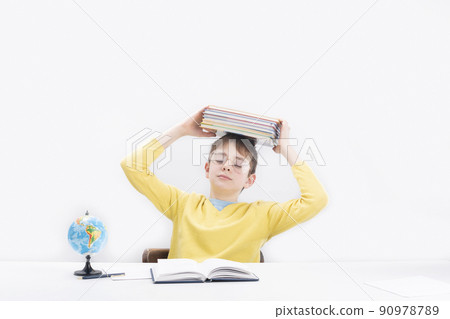 Tired schoolboy is holding stack of notebooks over his head. Schoolboy difficult does his homework. Bored education Tired schoolboy is holding stack of notebooks over his head. Schoolboy difficult does his homework. Bored education 90978789