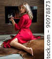Woman sitting by fireplace with glass of wine 90978873