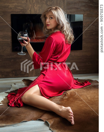 Woman sitting by fireplace with glass of wine Woman sitting by fireplace with glass of wine 90978873